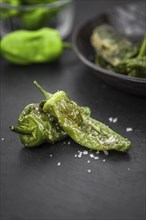 Portion of Pimientos de Padron on a rustic slate slab, selective focus, close-up shot