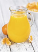 Homemade Tangerine Juice on an old and rustic wooden table (selective focus, close-up shot)