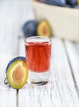 Plum Liqueur on rustic wooden background as close-up shot