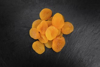 Portion of Dried Food (Apricots) as detailed close up shot on a slate slab (selective focus)