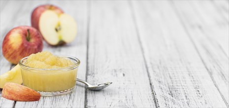 Portion of fresh made Applesauce (selective focus) on a wooden table