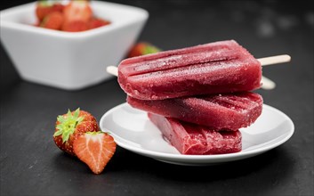 Homemade Strawberry Popsicles (close-up shot, selective focus) on vintage background