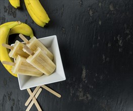 Homemade Banana Popsicles on a vintage background (close-up shot, selective focus)