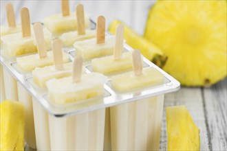 Some homemade Pineapple Popsicles (selective focus) on a rustic background