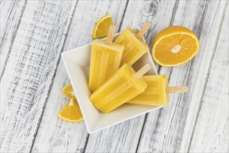 Orange Popsicles (selective focus, close-up shot) on a vintage background