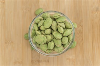 Peanuts (with Wasabi flavor) on an old wooden table as detailed close-up shot (selective focus)