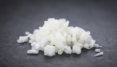 Portion of Chopped white onions as detailed close up shot on a slate slab, selective focus