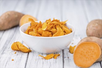 Sweet Potato Chips as high detailed close-up shot on a vintage wooden table, selective focus