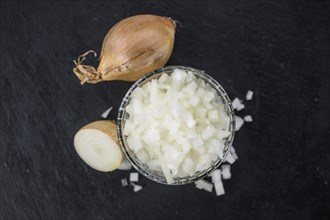 Some White Onions (dices) on a slate slab as detailed close-up shot, selective focus