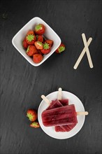 Homemade Strawberry Popsicles (close-up shot, selective focus) on vintage background