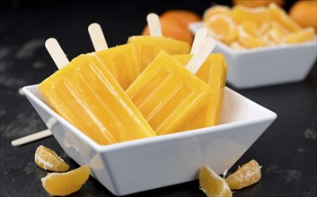 Homemade Tangerine Popsicles with some fresh fruits (close-up shot) on a vintage background