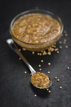 Portion of Mustard (sweet) as detailed close up shot on a slate slab (selective focus)