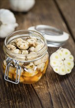 Garlic (preserved) as high detailed close-up shot on a vintage wooden table (selective focus)