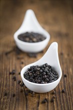 Wooden table with preserved black Peppercorns, selective focus, close-up shot