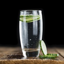 Fresh made Cucumber Water as high detailed close-up shot on a vintage wooden table, selective focus