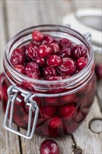 Old wooden table with fresh Preserved Cranberries (close-up shot, selective focus)