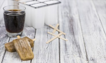 Fresh made Cola Popsicles on wooden background (selective focus, close-up shot)