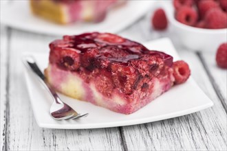 Fresh made portion of Raspberry Cake (selective focus, close-up shot) on rustic background