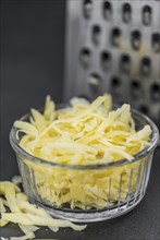 Homemade Grated Cheese (close-up shot) on a vintage slate slab