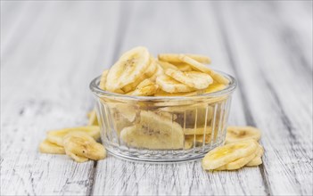 Homemade Dried Banana Chips on an wooden table as detailed close-up shot, selective focus