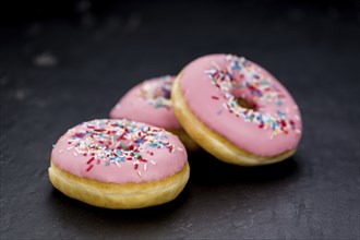 Portion of pink glazed Donuts (detailed close-up shot)