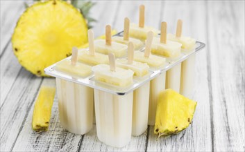 Old and rustic wooden table with homemade Pineapple Pipsicles (selective focus, close-up shot)