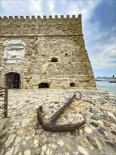 Old historical cane anchor made of iron slightly rusty in front of main gate entrance of fortress