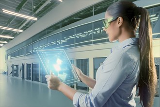 Woman in modern laboratory setup with tablet, surrounded by holographic representations and