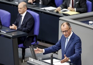 CDU parliamentary group leader Friedrich Merz, right, speaks in the Bundestag, in the background is