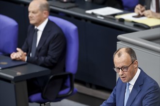 CDU parliamentary group leader Friedrich Merz, right, speaks in the Bundestag, in the background is