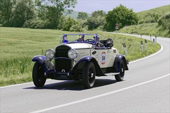 White vintage racing car driving along a country road, surrounded by green landscape, vintage car,