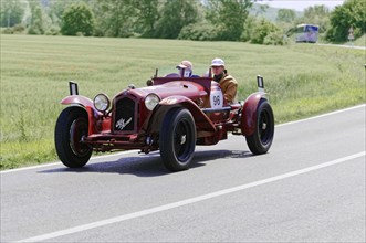 Red vintage car driving along a country road, with green landscape in the background, vintage car,