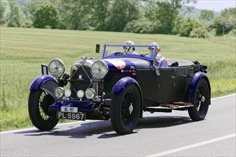 Black convertible with driver and passenger on a country road during a rally, classic car, car