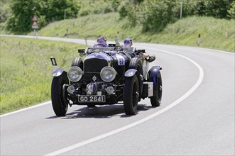 Black classic car with two people on a country road during a rally, classic car, car race, Mille