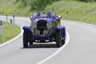 Black and purple vintage car with two people in a bend on a country road during a rally, vintage