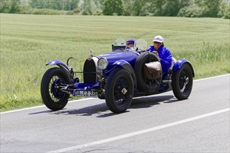 Blue vintage car with two people on a country road during a rally, vintage car, car race, Mille