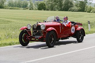 Red classic car with driver and co-driver on a country road during a rally, classic car, car race,