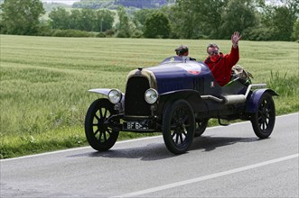 Black vintage car with two people on a country road during a rally. Driver waving, classic car, car