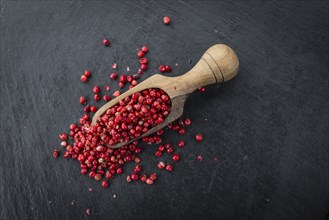 Portion of Pink Peppercorns as detailed close up shot on a slate slab, selective focus