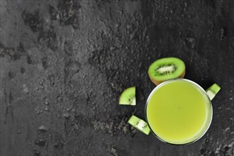 Some fresh homemade Kiwi Smoothies on a slate slab (close-up shot, selective focus)