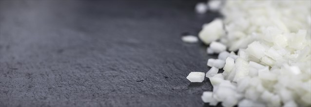 Portion of Chopped white onions as detailed close up shot on a slate slab, selective focus