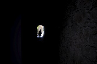 Woman Walking in a Dark Tunnel with Sunlight in Gandria, Ticino, Switzerland, Europe