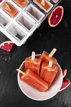 Vintage slate slab with some freshly made Grapefruit Popsicles (selective focus, close-up shot)