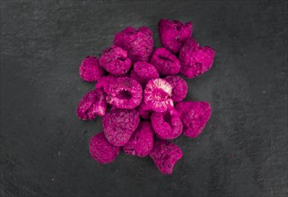 Dried Raspberries on a vintage slate slab as detailed close-up shot, selective focus