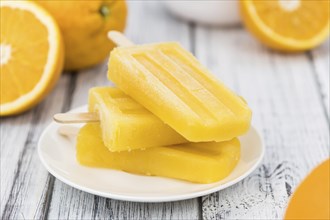 Some homemade orange popsicles (selective focus) on a vintage background