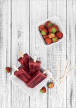 Homemade Strawberry Popsicles (close-up shot, selective focus) on vintage background