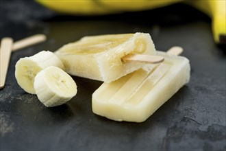 Homemade Banana Popsicles on a vintage background (close-up shot, selective focus)