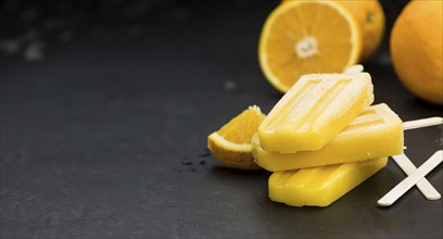 Some homemade orange popsicles on a vintage background (selective focus, close-up shot)