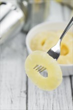 Preserved Pineapple Rings on an old wooden table as detailed close-up shot, selective focus