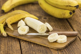 Sliced Bananas as high detailed close-up shot on a vintage wooden table, selective focus